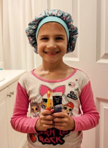 Image: A little girl holds a tube of Dr. Bob Unflavored Fluoridated Toothpaste