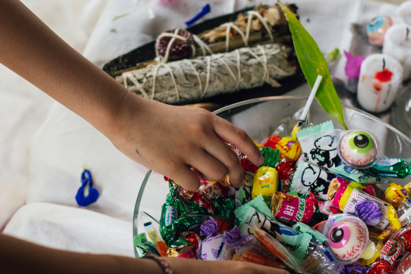 Image: Two children reaching into a bowl of Halloween candy