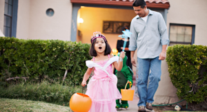 Image: A little girl trick-or-treating with her dad