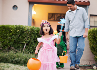 Trick-or-Treating: How It Became an American Tradition | Dr. Bob Image: A little girl trick-or-treating with her dad