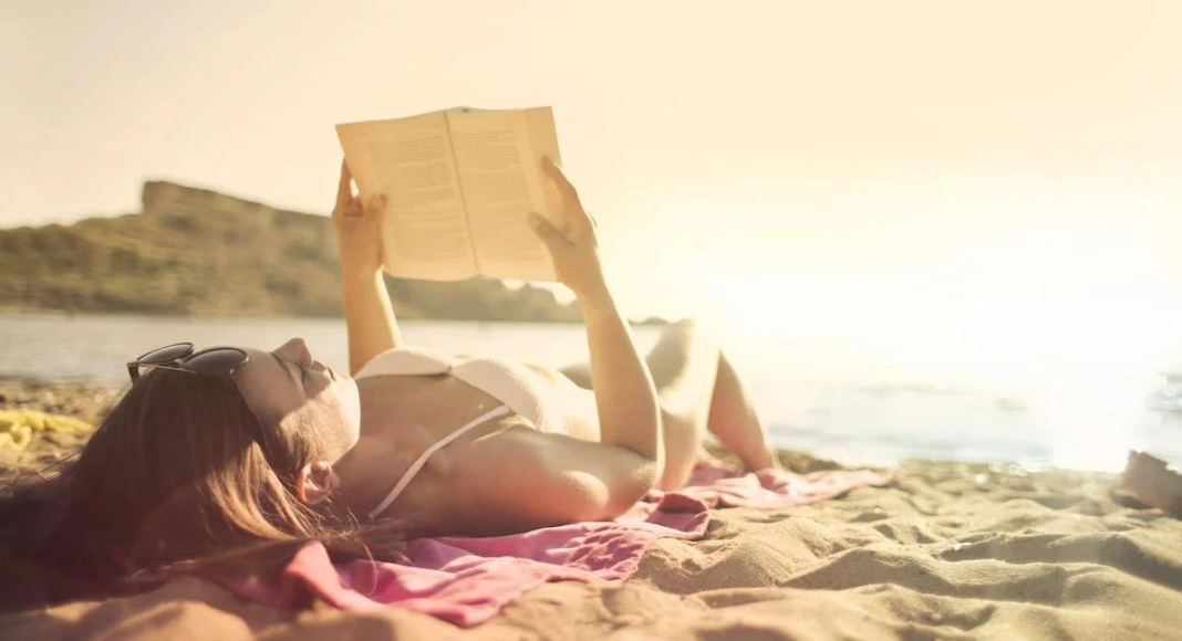 Image: A woman reading a book at the beach