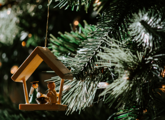 Learning to Love My Actual Christmas: A Letter to Weary Moms A wooden nativity ornament hanging on a Christmas tree