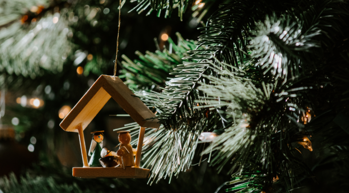 A wooden nativity ornament hanging on a Christmas tree