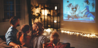 A family sitting on the couch, watching a movie together
