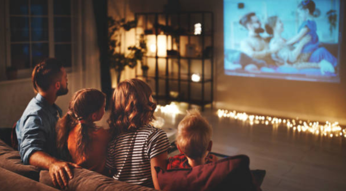 A family sitting on the couch, watching a movie together