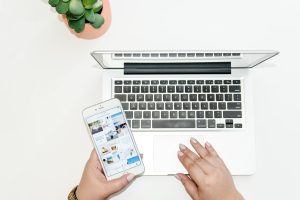 A woman using her laptop while she looks something up on her smartphone