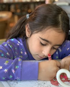 A child using a crayon on a coloring page.