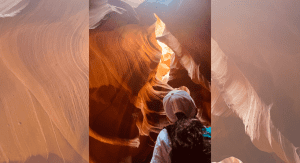 A child looks up at the sunlight shining through a canyon