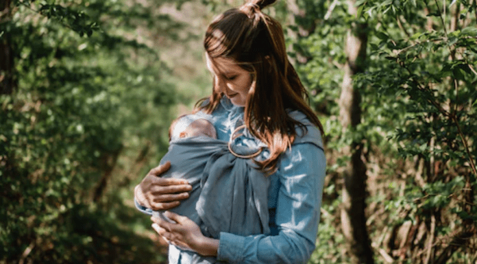 Post-Partum Crisis: Is This a Thing? A postpartum mom wearing her newborn baby in a sling