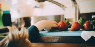A toddler reaches to grab some fresh fruit