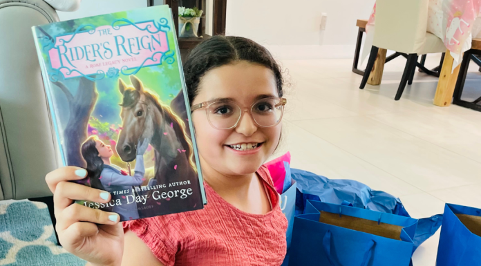 An almost middle school student holding up a new book