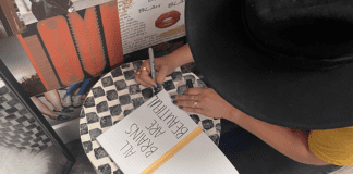 A woman writing in a journal that reads, "All brains are beautiful," a statement of support for neurodiversity