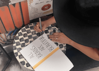 A woman writing in a journal that reads, "All brains are beautiful," a statement of support for neurodiversity
