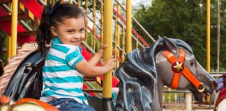 A little girl riding on a carousel at a theme park