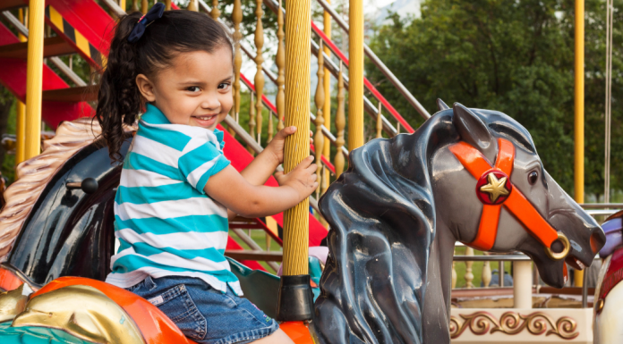 A little girl riding on a carousel at a theme park