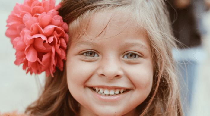 A little girl with a flower in her hair, showing off her smile