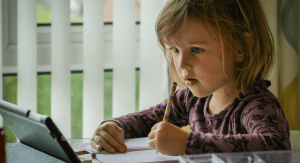 A little girl works on a lesson on her device