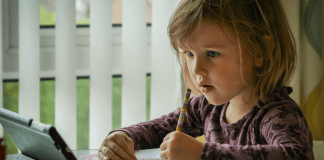 A little girl works on a lesson on her device