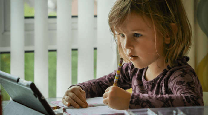 A little girl works on a lesson on her device