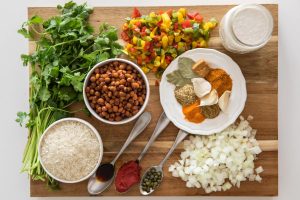 A wooden cutting board containing all of the ingredients for this arroz con gandules recipe