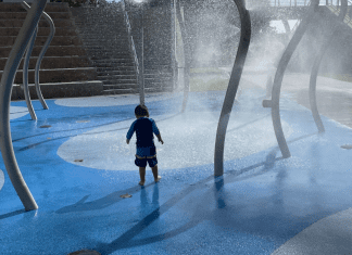 A little boy enjoying a splash pad at a local playground