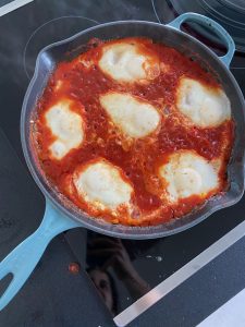 A frying pan with marinara sauce and mozzarella cheese