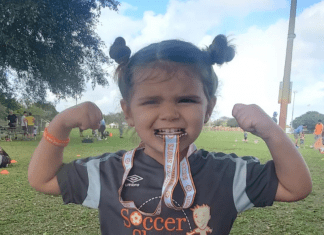 I Learned to Love ME Because of YOU Little girl biting a soccer medal and showing her muscles