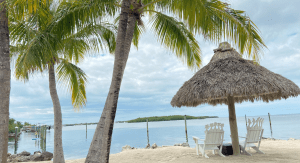 Two beach chairs under a chiki umbrella on a beach in Islamorada