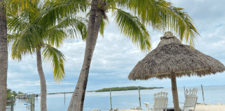 Two beach chairs under a chiki umbrella on a beach in Islamorada