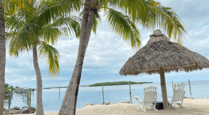 Two beach chairs under a chiki umbrella on a beach in Islamorada
