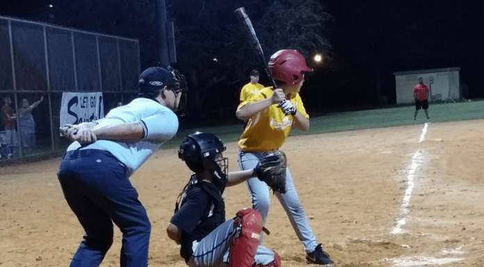 Little league baseball players standing behind home plate