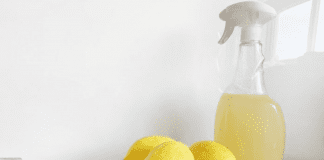 A few lemons next to a spray bottle of lemon juice on a kitchen counter
