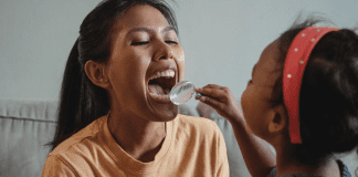 5 Things Your Child’s Dentist Wishes You Knew | Dr. Bob Pediatric Dentist A young girl plays dentist with her mom, holding a magnifying glass up to check her teeth