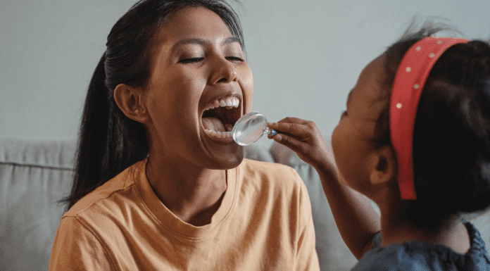 5 Things Your Child’s Dentist Wishes You Knew | Dr. Bob Pediatric Dentist A young girl plays dentist with her mom, holding a magnifying glass up to check her teeth