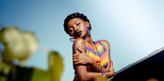 A woman in a brightly colored dress, giving herself a hug