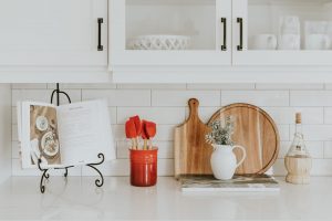 A cookbook, cutting board, and some kitchen utensils on a counter