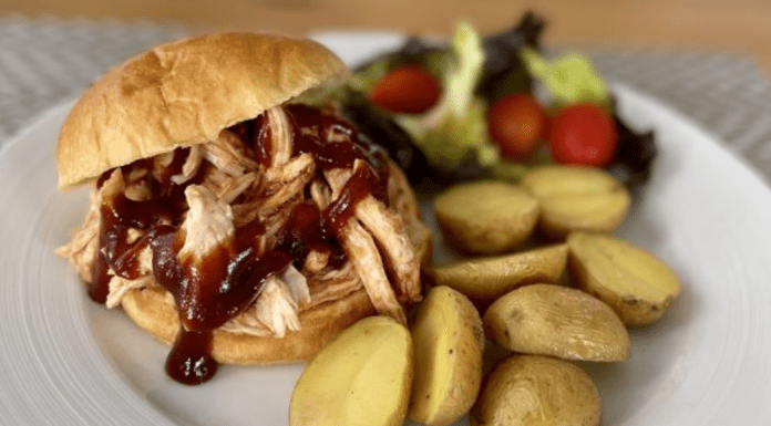 A BBQ pulled chicken sandwich, served with roasted potatoes and salad