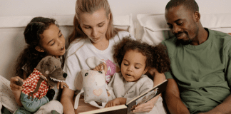 Image: A multi-racial family sitting a reading a book together