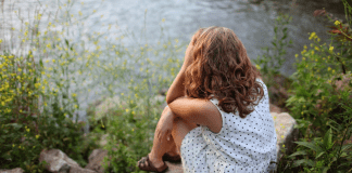 Image: A woman sits beside a lake (Toxic Positivity: How to Stay True to Yourself Bella Behar Contributor Miami Mom Collective)