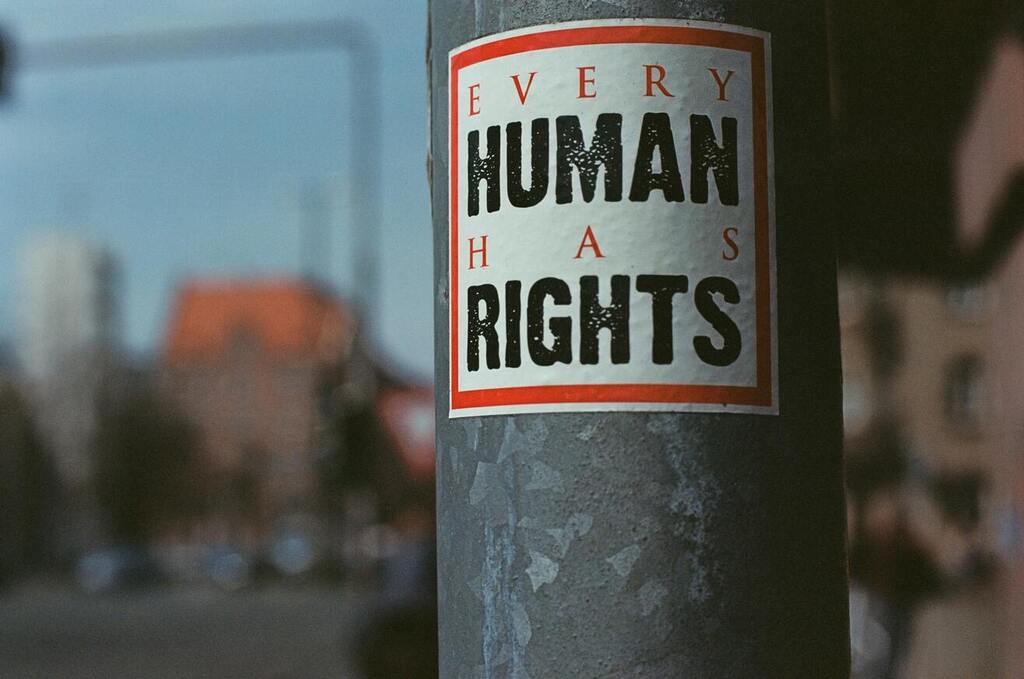 Image: A sticker on a signpost that reads, "Every human has rights"