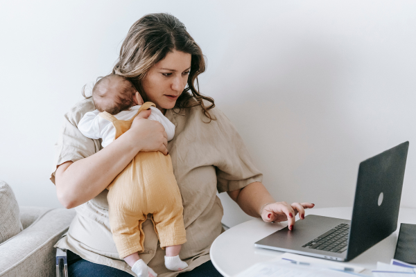 Image: A mom holds her newborn while she gets some work done (5 Tips for the Momtrepreneur Minnie Roca Contributor Miami Mom Collective)