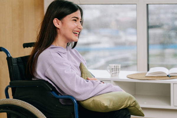Image: A young, smiling woman sitting in a wheelchair
