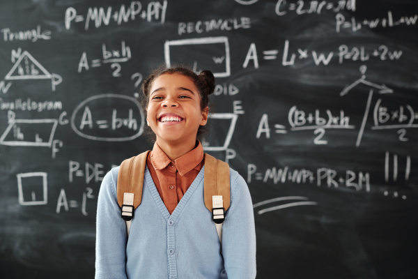 Image: A child smiling in front of a blackboard