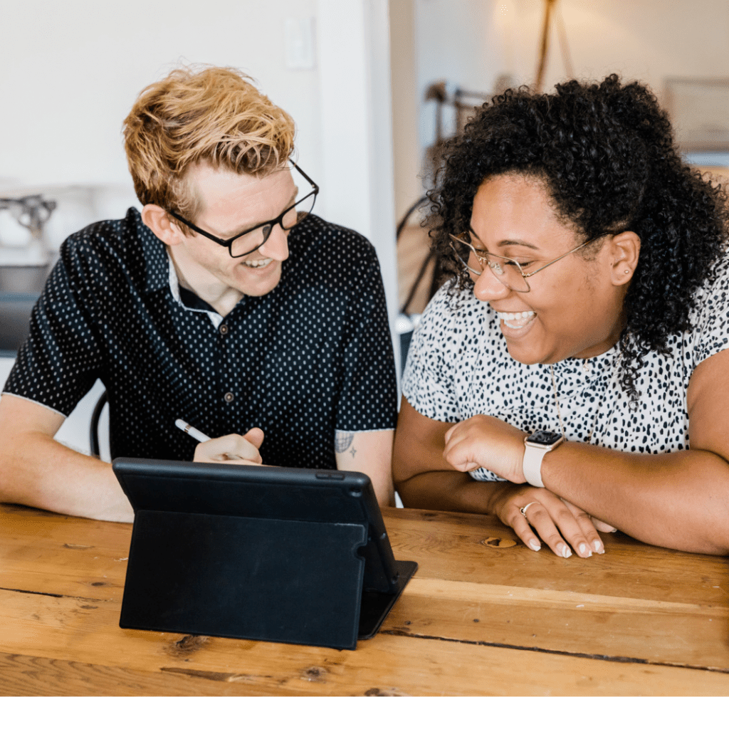 Image: two people smiling as they sit together in front of a tablet (Giving Tuesday 2021: A Global Effort to Bring the World Together Sharonda Stewart Contributor Miami Mom Collective)