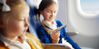 Image: Two girls sitting together on an airplane (Holiday Travel: The Ultimate Prep List for Smooth Family Travel Vanessa Santamaria Contributor Miami Mom Collective)