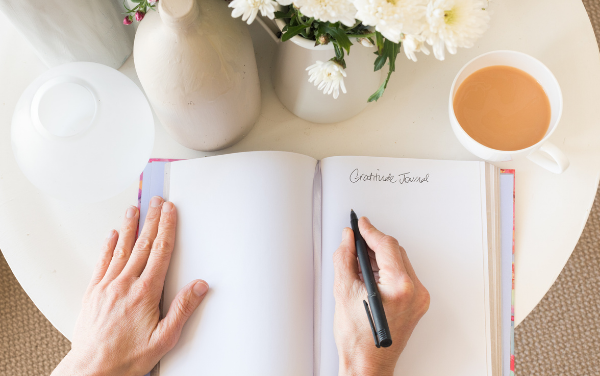 Image: Someone writing in a gratitude journal (Lorena Lougedo Contributor Miami Mom Collective)