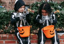 Allergy-Friendly Halloween: Tricks and Treats Image: Two girls in skeleton costumes sitting with their Halloween buckets