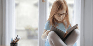 Image: A little girl reading a book (October is Dyslexia Awareness Month Sharonda Stewart Contributor Miami Mom Collective)