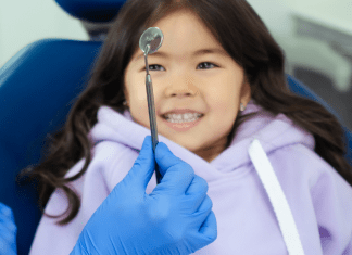 A young girl at the dentist's office (Going Back to the Dentist? 3 Things to Consider | Dr. Bob Pediatric Dentist Lynda Lantz Contributor Miami Mom Collective)