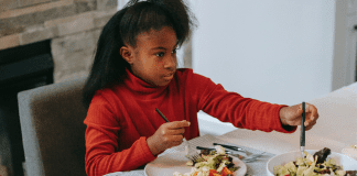 Image: A school-aged girl sitting at a table eating (Raising a Diverse Eater: 3 Keys to Success Dina Garcia Contributor Miami Mom Collective)